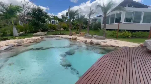 Piscina natural com pedras, deck de madeira e jardim em residência de Gravatá