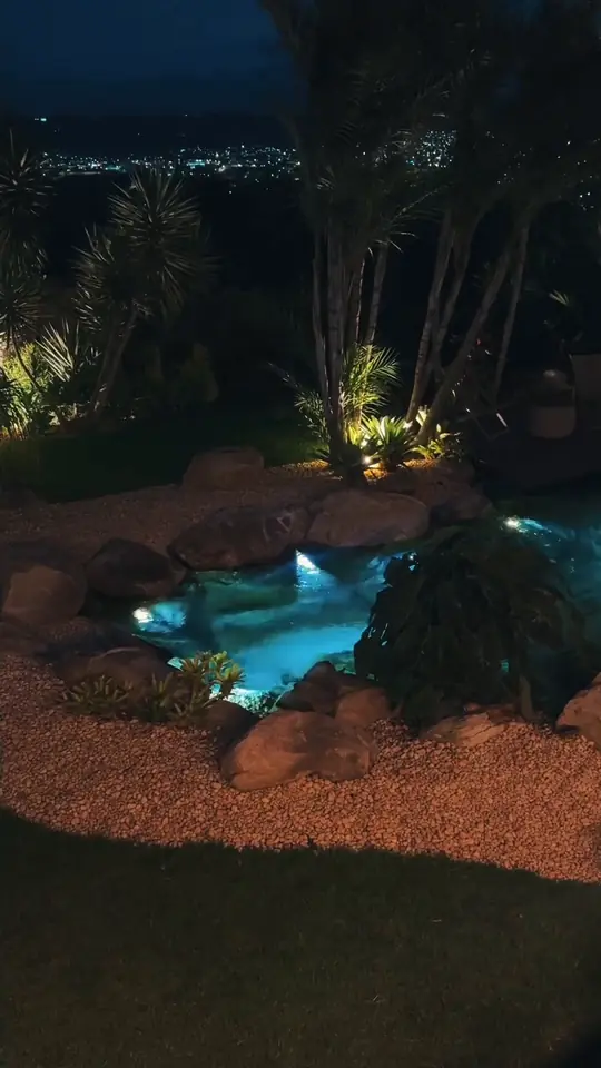 Lago ornamental iluminado à noite entre palmeiras